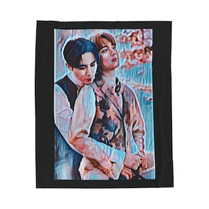 May include: A blanket featuring a digital art print of two people embracing. One person wears a floral patterned jacket, the other a vest over a white shirt. The blanket has a black border and a painterly style.