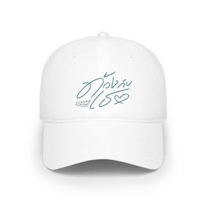 May include: A white baseball cap with a curved brim. The cap features teal script and a heart-shaped design. The text on the cap reads "Duang Lucky You".