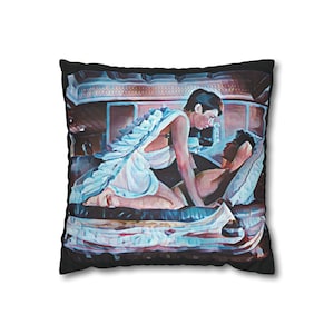 May include: Square pillow with a digitally painted image of two people in a romantic embrace. One person is kneeling, wearing a white toga with feathered wings. The other is reclining on a bed. The pillow has a black border.
