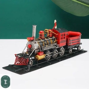 Peut inclure: Un modèle de train en métal rouge et noir avec un wagon à charbon. Le train est sur une voie en métal noir.