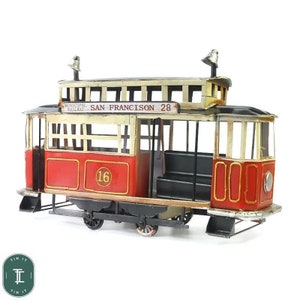 May include: A red and cream vintage toy model of a San Francisco Municipal Railway streetcar. The streetcar has the number 28 on the side and the number 16 on the front.