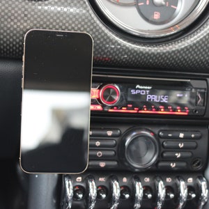 Peut inclure: Un smartphone noir est mont&eacute; sur le tableau de bord d'une voiture, &agrave; c&ocirc;t&eacute; d'un autoradio Pioneer avec les mots "SPOT" et "PAUSE" affich&eacute;s &agrave; l'&eacute;cran.