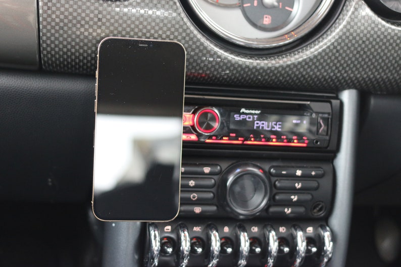 Peut inclure: Un smartphone noir est mont&eacute; sur le tableau de bord d'une voiture, &agrave; c&ocirc;t&eacute; d'un autoradio Pioneer avec les mots "SPOT" et "PAUSE" affich&eacute;s &agrave; l'&eacute;cran.
