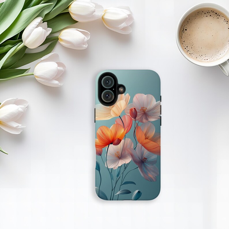 May include: A teal phone case featuring a floral design with orange, pink, and white flowers. The case has a dual-lens camera cutout and is surrounded by a black border. White tulips and a cup of coffee are in the background.