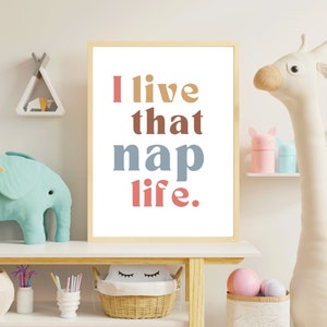 May include: A framed print with the text "I live that nap life." in a colorful, modern font. The words are in different colors: "I" is red, "live" is orange, "that" is brown, "nap" is blue, and "life" is pink.
