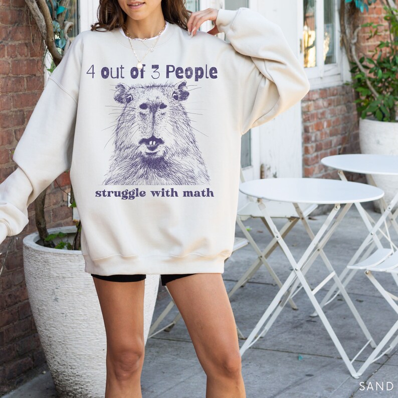 May include: A cream-colored sweatshirt with a graphic of a capybara and the text "4 out of 3 People struggle with math".