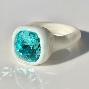 Puede incluir: Un anillo de cerámica blanca con una gran piedra turquesa de forma cuadrada.