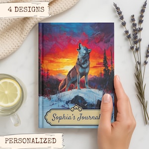 May include: A personalized journal with a vibrant painting of a howling wolf against a sunset backdrop. The journal cover features the text "Sophia's Journal" in an ornate frame. The words "4 DESIGNS" and "PERSONALIZED" are also visible.