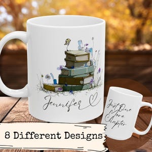 May include: White ceramic mug featuring a stack of books with a bird and floral illustrations. The mug has the name "Jennifer" and a heart symbol. A smaller mug displays the text "Just One More Chapter".