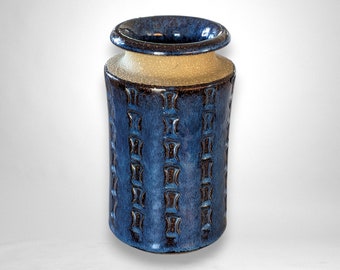 Könnte beinhalten: Eine blaue und weiße Keramikvase mit geometrischem Muster. Die Vase hat eine breite Öffnung und einen zylindrischen Körper.