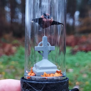 Bat automaton. Bat flying above a gravestone. Kinetic sculpture made from metal, paper, glass and velvet.