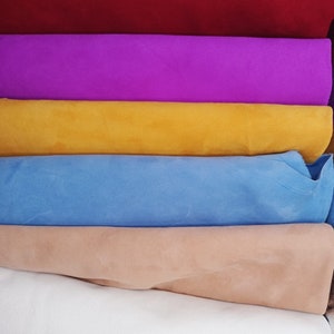 May include: A stack of six fabric swatches in different colors. The colors are red, purple, yellow, light blue, beige, and white.