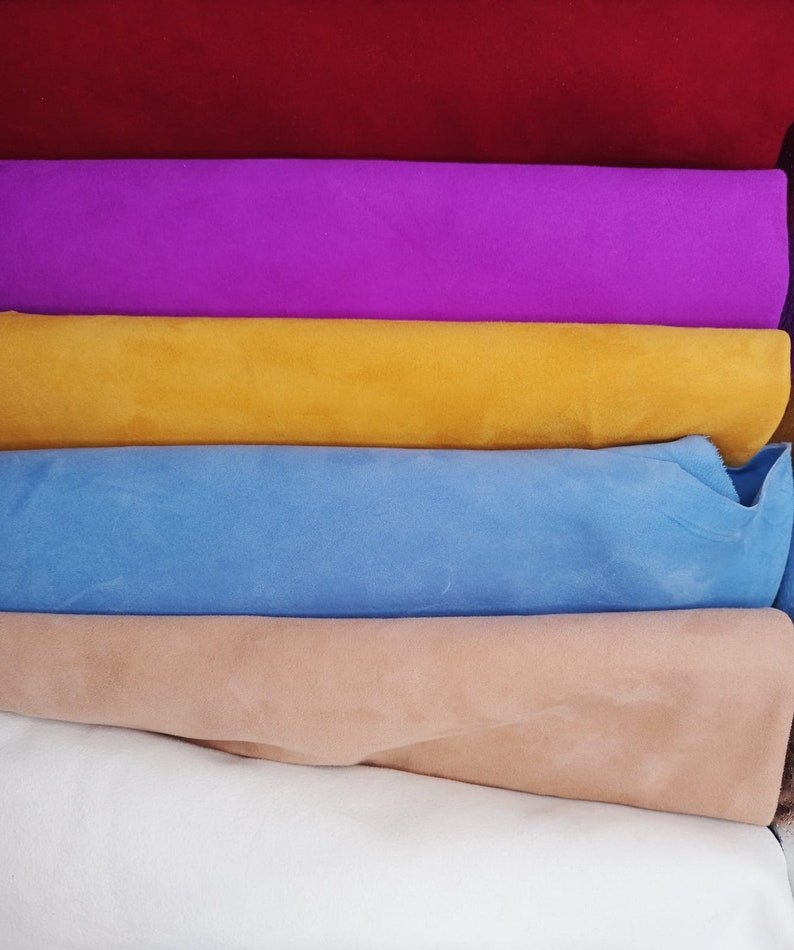 May include: A stack of six fabric swatches in different colors. The colors are red, purple, yellow, light blue, beige, and white.