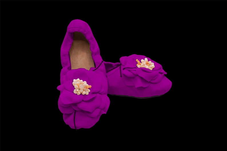 May include: A pair of purple satin slippers with a flower design and pearl embellishments.