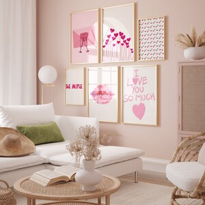May include: A pink living room with a white sectional sofa, a coffee table, and a wicker chair. The walls are decorated with framed prints featuring hearts, lips, and the text "Be Mine" and "I Love You So Much".