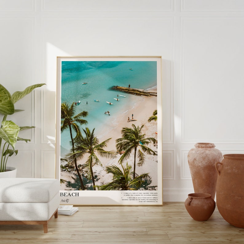 May include: A framed print featuring a beach scene with turquoise water, white sand, and palm trees. The image includes people swimming and surfing. The word "BEACH" is printed at the bottom, along with a definition.