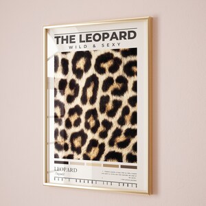 May include: A gold framed poster with the text "THE LEOPARD WILD & SEXY" and a close-up image of a leopard's fur pattern. The poster also includes the word "LEOPARD" and the phonetic pronunciation "/ˈlepərd/" along with a description of the animal's spots.
