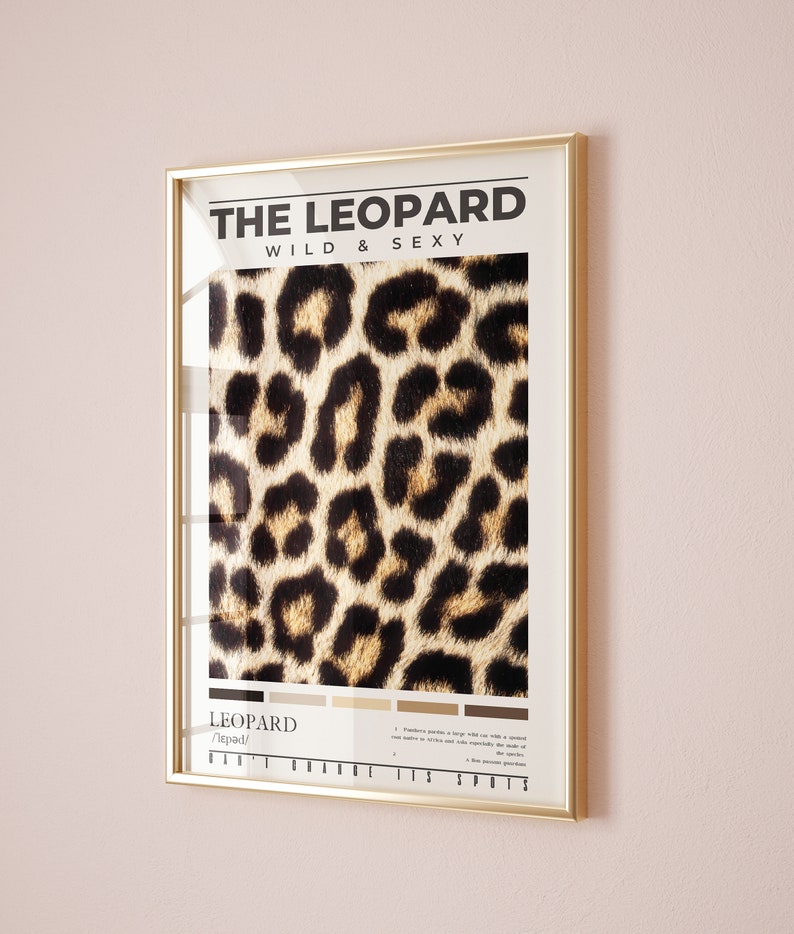 May include: A gold framed poster with the text "THE LEOPARD WILD & SEXY" and a close-up image of a leopard's fur pattern. The poster also includes the word "LEOPARD" and the phonetic pronunciation "/ˈlepərd/" along with a description of the animal's spots.