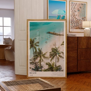 May include: Three framed beach-themed prints. The largest features a tropical beach scene with palm trees, turquoise water, and the word "BEACH". The other two prints show beach scenes with umbrellas and beachgoers. All are in wooden frames.