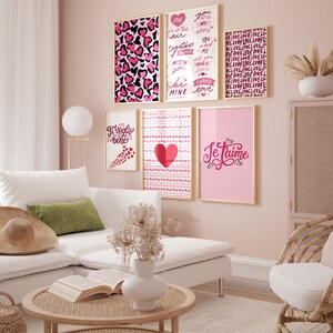 May include: A pink wall with six framed prints featuring various love-themed designs. The prints include hearts, text, and a leopard print pattern. The prints are arranged in a grid pattern on the wall.