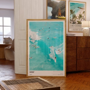May include: A framed poster with a turquoise blue background featuring a group of surfers riding waves. The poster has the word "SURF" in white text at the bottom and the text "1327" in smaller white text below the word "SURF".