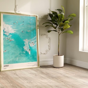 May include: A framed poster with a turquoise blue background featuring a group of surfers riding waves. The poster has the word "SURF" in white text at the bottom and the text "NEXT" in smaller white text below the word "SURF".