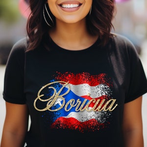 Puede incluir: Camiseta negra con un dise&ntilde;o de la bandera puertorrique&ntilde;a en purpurina dorada y la palabra "Boricua" en purpurina dorada.
