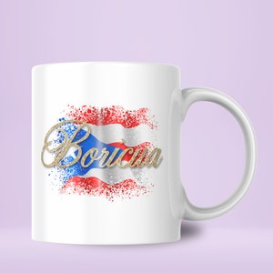 Puede incluir: Taza de cer&aacute;mica blanca con un dise&ntilde;o de la bandera puertorrique&ntilde;a en purpurina dorada y la palabra "Boricua" en purpurina dorada.