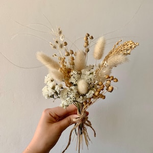 Puede incluir: Un peque&ntilde;o ramo de flores secas en tonos blancos y beige. El ramo incluye hierbas secas, hierba de la pampa y aliento de beb&eacute; blanco.