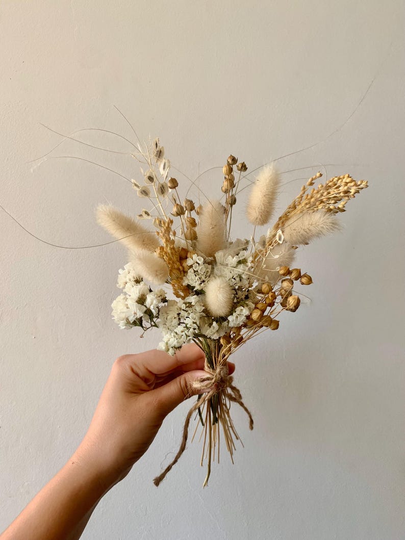 Puede incluir: Un peque&ntilde;o ramo de flores secas en tonos blancos y beige. El ramo incluye hierbas secas, hierba de la pampa y aliento de beb&eacute; blanco.