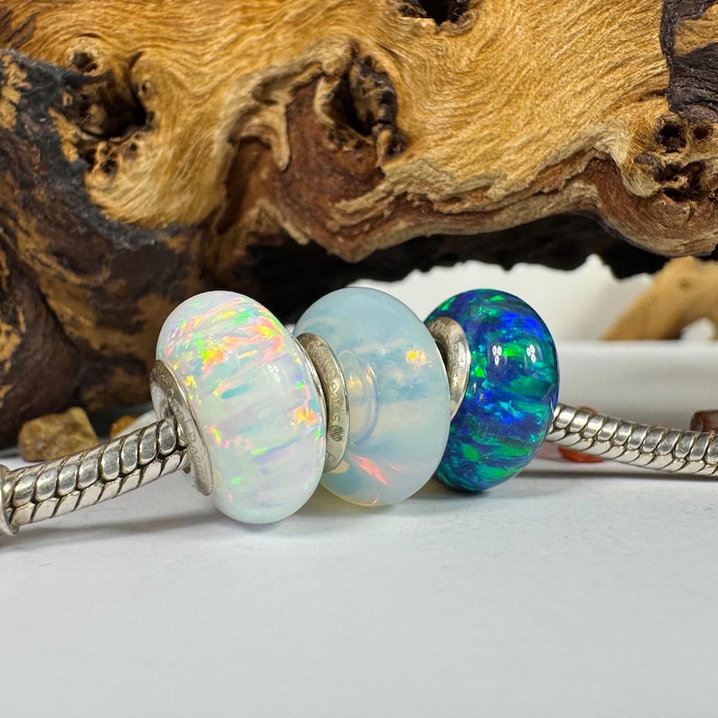 May include: Three glass beads, one white opal, one white opal with iridescent rainbow colors, and one blue opal with green streaks. The beads are on a silver chain.
