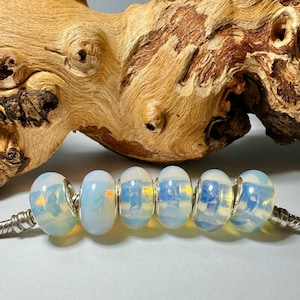 May include: A strand of six iridescent opal beads with silver spacers. The beads are a milky white with a blue and yellow iridescent sheen.