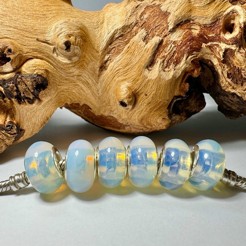 May include: A strand of six iridescent opal beads with silver spacers. The beads are a milky white with a blue and yellow iridescent sheen.