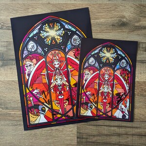 May include: Two framed prints of a stained glass window design featuring a red-haired character with wings and a halo. The design is set against a black background with a gold halo and a red, orange, and yellow stained glass pattern.