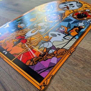 May include: A colourful sticker with a stained-glass style design, featuring cartoon characters. The sticker has an orange border and a glossy finish. The artwork includes shades of orange, blue, white, and purple, creating a vibrant and detailed image.