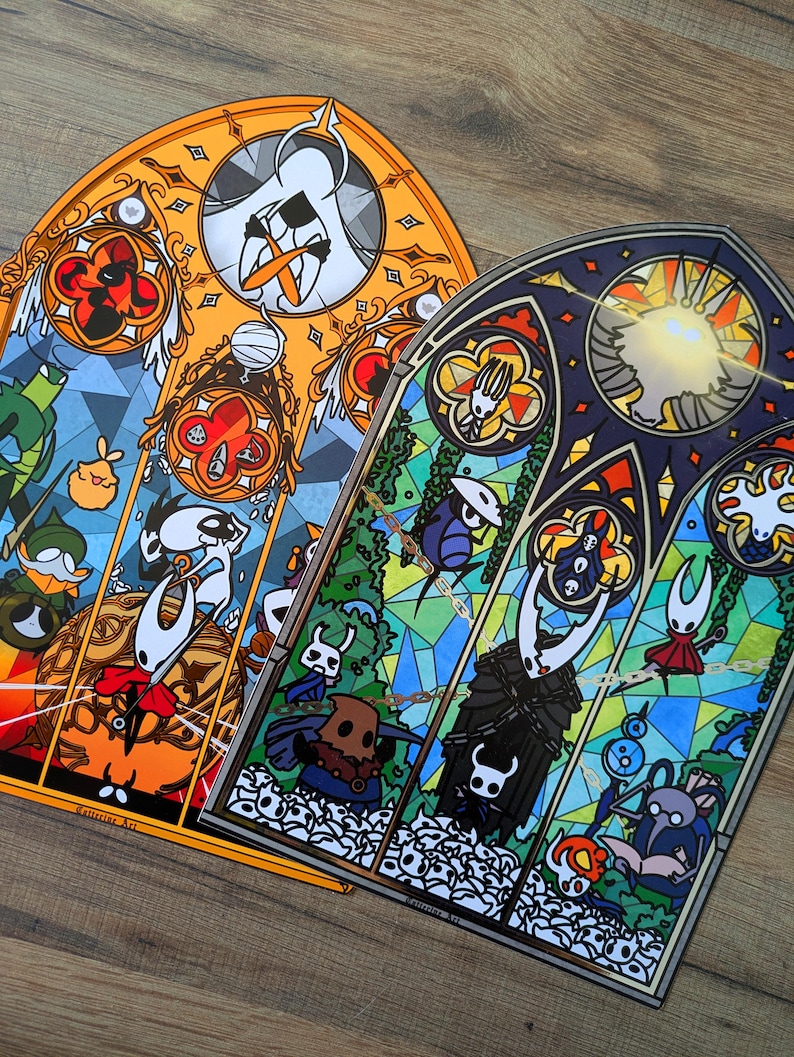 May include: Two stained-glass style art prints featuring characters from a video game. One print has an orange border, the other a blue border. Each print has a variety of characters and shapes in a stained-glass style.