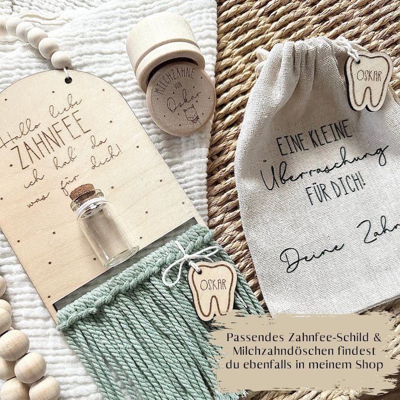 May include: A wooden tooth fairy box with a small glass bottle, a green tassel, and a wooden tooth charm with the name "OSKAR" on it. The box has the text "Hallo liebe Zahnfee, ich hab da was f&uuml;r dich!" on it. There is also a small white bag with the text "Eine kleine &Uuml;berraschung f&uuml;r dich!" on it.