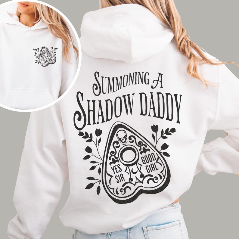 Puede incluir: Sudadera con capucha blanca con un gr&aacute;fico negro en la espalda que dice "Summoning a Shadow Daddy" y un dise&ntilde;o de planchette. La parte delantera de la sudadera tiene un dise&ntilde;o de planchette m&aacute;s peque&ntilde;o. La sudadera tiene capucha y bolsillo delantero.