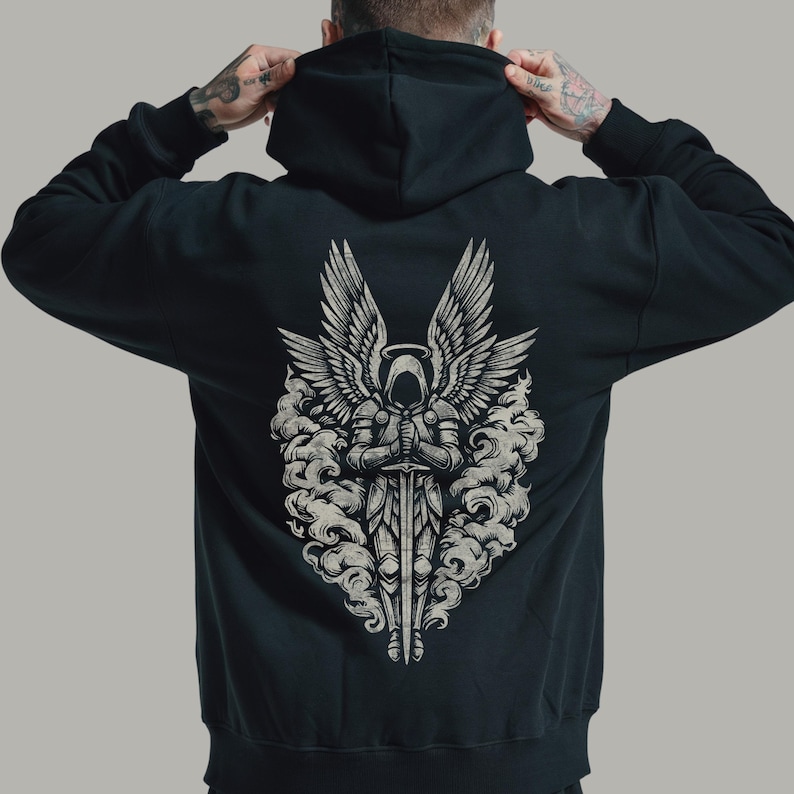 Op de afbeelding: Zwarte hoodie met een gedetailleerde afbeelding op de rug. De afbeelding toont een engel met grote vleugels, een halo en een zwaard, omringd door wolkvormige vormen. Het ontwerp is in grijstinten en wit.