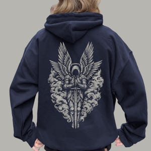 Op de afbeelding: Marineblau hoodie met een gedetailleerde afbeelding van een engel met een zwaard, omringd door wolken. De engel heeft grote vleugels en een halo. Het ontwerp is in grijstinten en wit, wat contrasteert met de donkerblauwe stof.