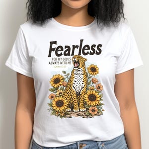 May include: White t-shirt with a graphic of a leopard surrounded by sunflowers. The text "Fearless" is above the leopard, with the phrase "For my God is always with me" and the Bible verse Isaiah 41:10 below.