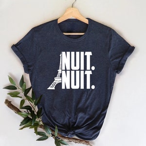 May include: A dark blue t-shirt with a white graphic of the Eiffel Tower and the text "NUIT. NUIT."