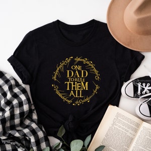 May include: Black t-shirt with a gold graphic of a ring with the text "One Dad To Rule Them All".