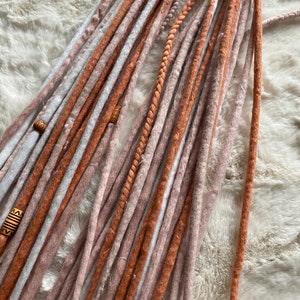 May include: A set of brown, white and light brown synthetic dreadlocks with wooden beads.