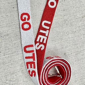 May include: Two beaded straps with gold clasps. The straps are red and white and say "GO UTES" in white letters on a red background and red letters on a white background.