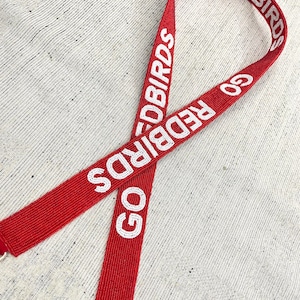 May include: Red beaded lanyard with the words "GO REDBIRDS" in white beads.