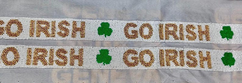 Puede incluir: Pancarta blanca de cuentas con las palabras "Go Irish" repetidas dos veces, con un tr&eacute;bol verde entre cada frase.