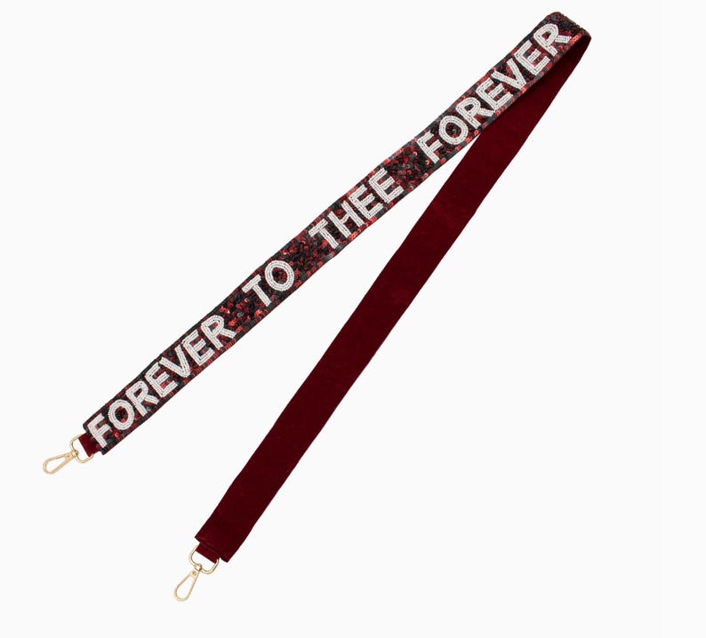 May include: A red velvet and sequined bag strap with gold clasps. The strap features the text "FOREVER TO THEE FOREVER" in white.