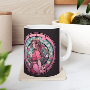 May include: White ceramic mug with a black background and a colourful stained glass design featuring a woman with long brown hair and a pink dress. The design is surrounded by a circle of pink and blue flowers.