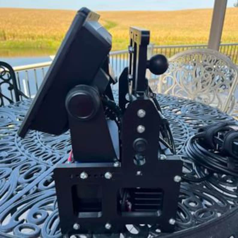 K&ouml;nnte beinhalten: Eine schwarze Metallhalterung mit einem gro&szlig;en Bildschirm daran. Die Halterung hat einen Knopf zum Einstellen des Bildschirmwinkels und ein Kugelgelenk zum Schwenken. Der Bildschirm ist mit einem schwarzen Kabel verbunden.